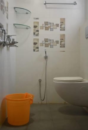 A bathroom with a toilet, shower, and a glass shelf.