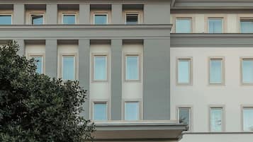 A hotel with a symmetrical facade, large windows, a central entrance with a glass door, and a landscaped courtyard.