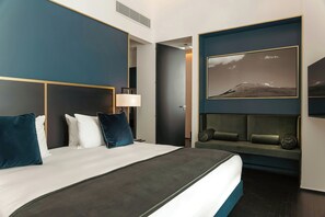 A modern hotel room with a large bed, a seating area with cushions, a framed picture on the wall, and a door leading to another room. - HABITA79, Pompeii, a Tribute Portfolio Hotel (Pompei)