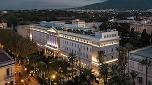 A large hotel with multiple floors, a prominent entrance, and a view of a mountain in the background. - HABITA79, Pompeii, a Tribute Portfolio Hotel (Pompei)