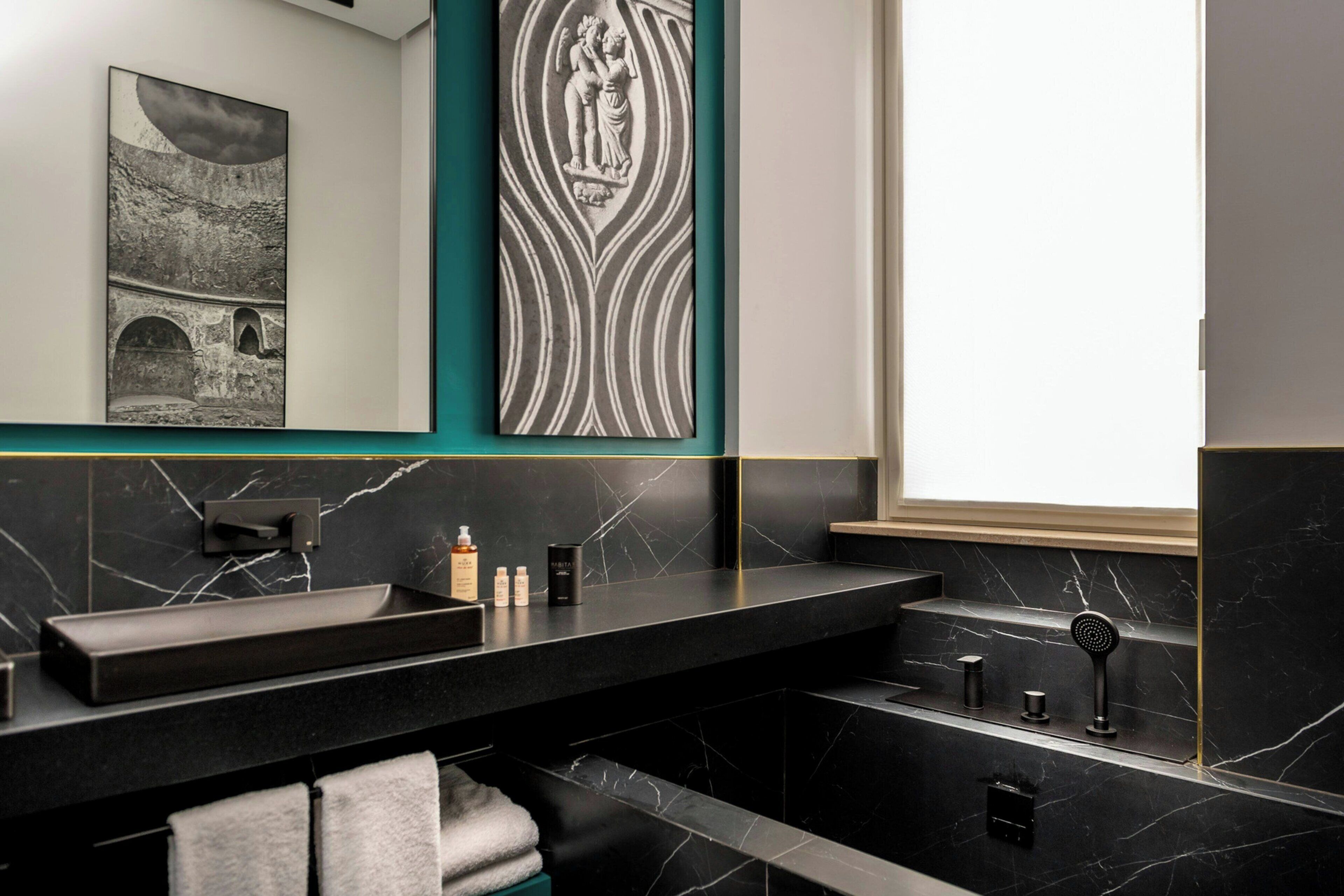 A modern bathroom with a black marble sink, a towel rack, and a decorative wall piece.