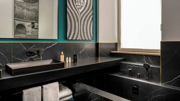 A modern bathroom with a black marble sink, a towel rack, and a decorative wall piece.