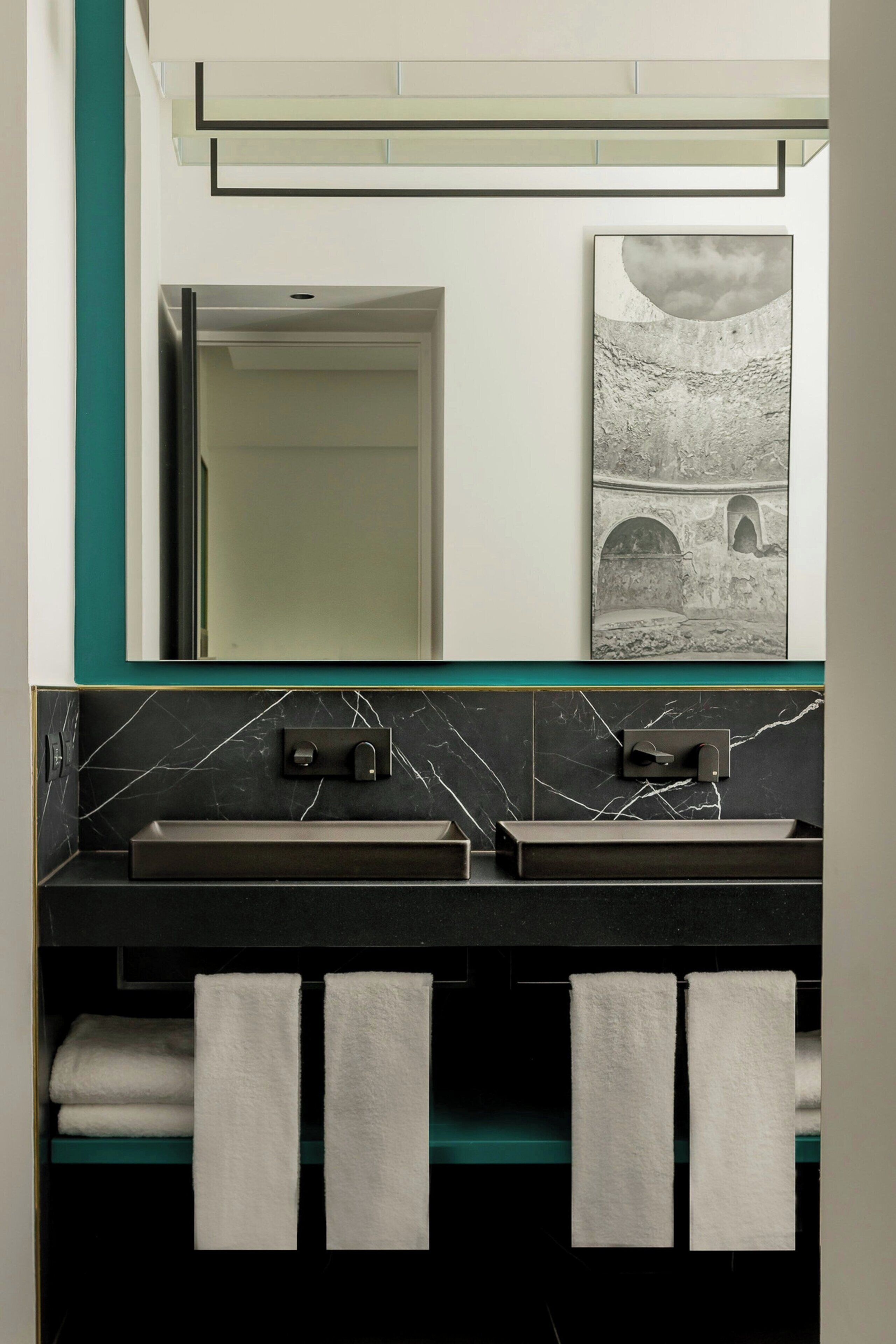A bathroom with two sinks, a mirror, and a towel rack with towels.