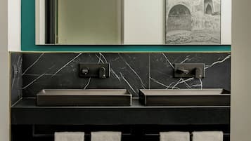 A bathroom with two sinks, a mirror, and a towel rack with towels.