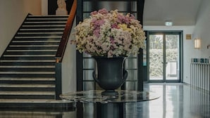 A modern lobby with a staircase, a statue, a floral arrangement, and a unique ceiling light fixture. - HABITA79, Pompeii, a Tribute Portfolio Hotel (Pompei)