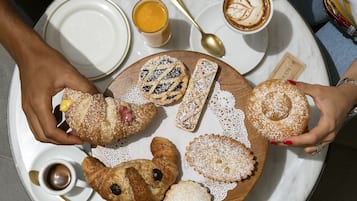 A round table with pastries, a cup of coffee, and a glass of juice.