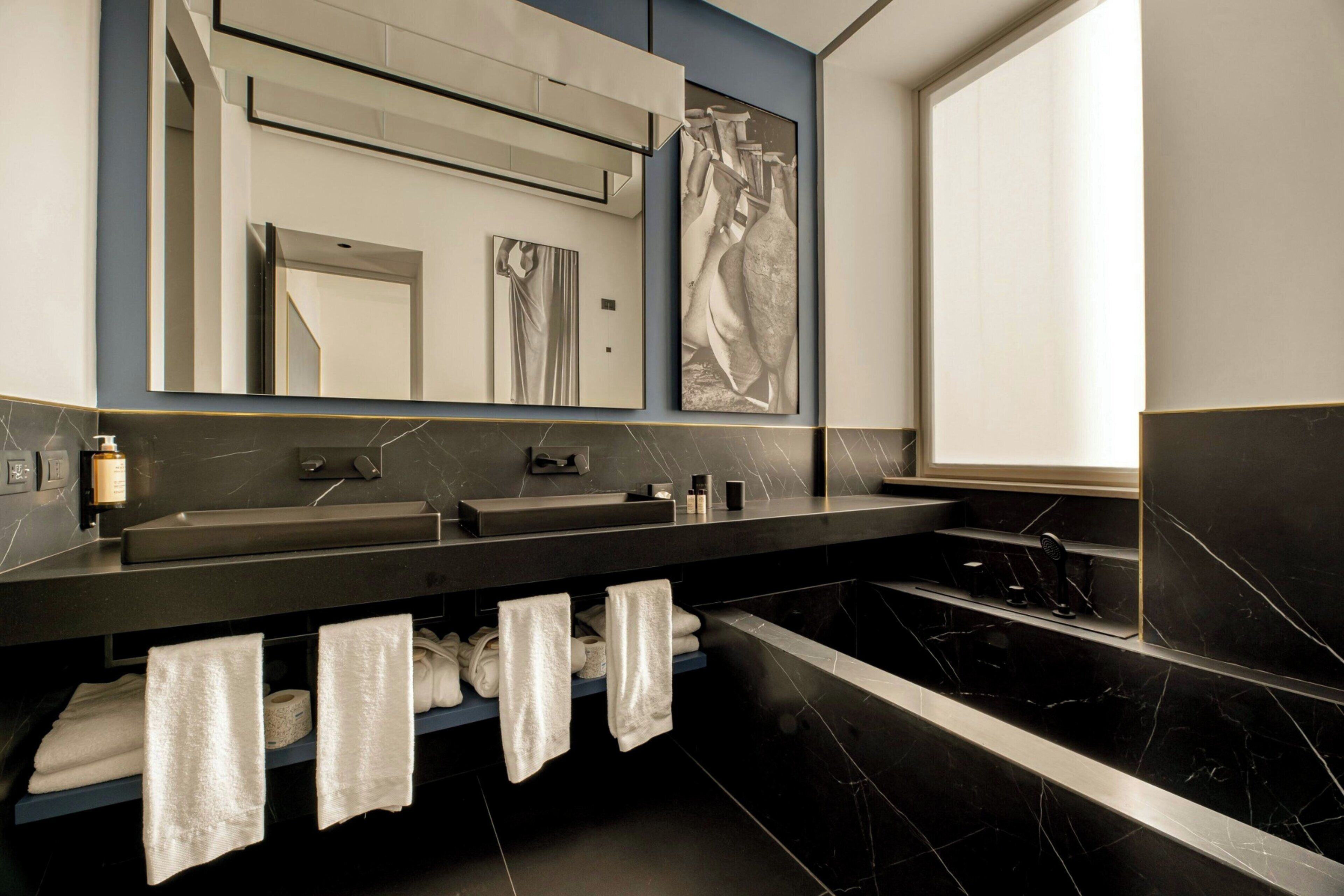 A modern bathroom with a dual sink vanity, a large mirror, and a bathtub.