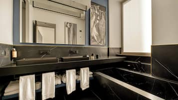 A modern bathroom with a dual sink vanity, a large mirror, and a bathtub.