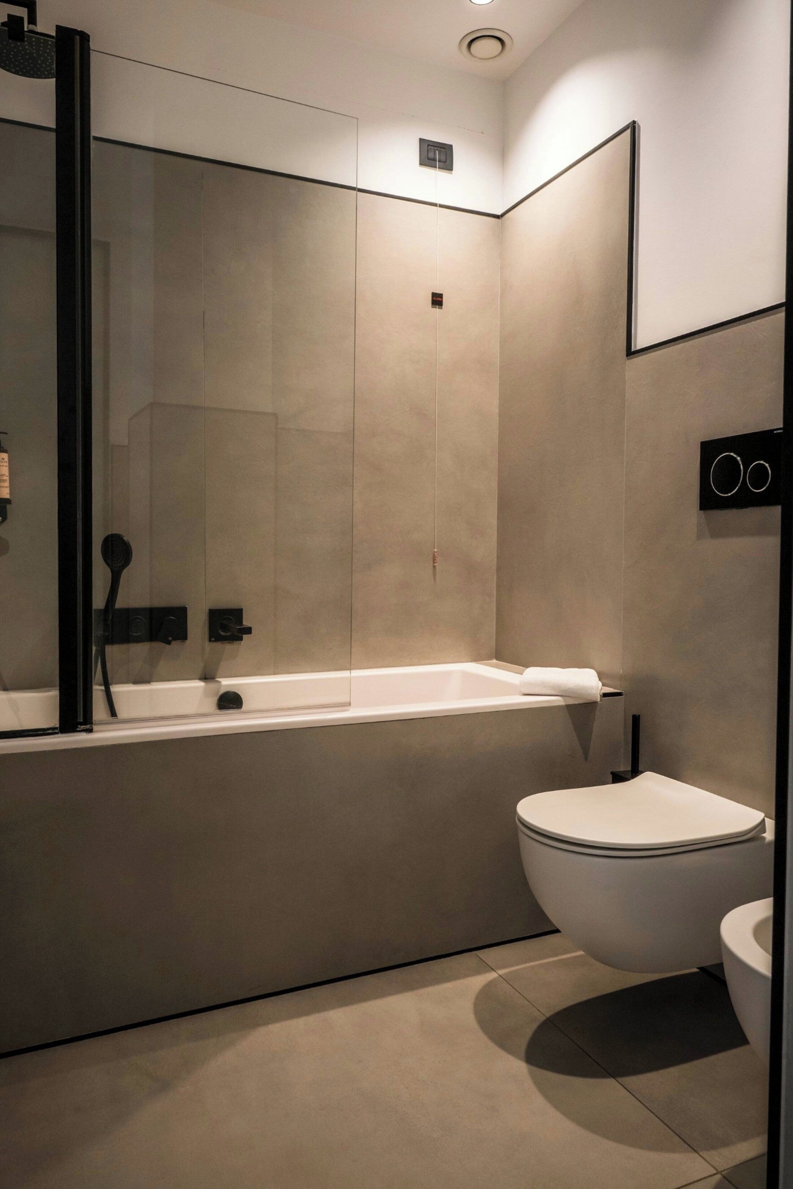 A modern bathroom with a glass-enclosed shower, a standalone bathtub, and a toilet.