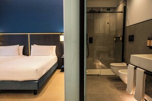 A modern hotel room with a bed, a nightstand, a glass-enclosed shower, a toilet, and a sink. - HABITA79, Pompeii, a Tribute Portfolio Hotel (Pompei)