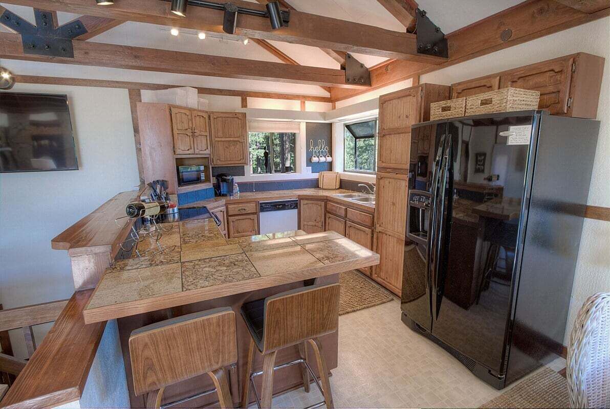 Une cuisine moderne dotée d’un grand îlot central, de meubles en bois et d’un réfrigérateur noir.