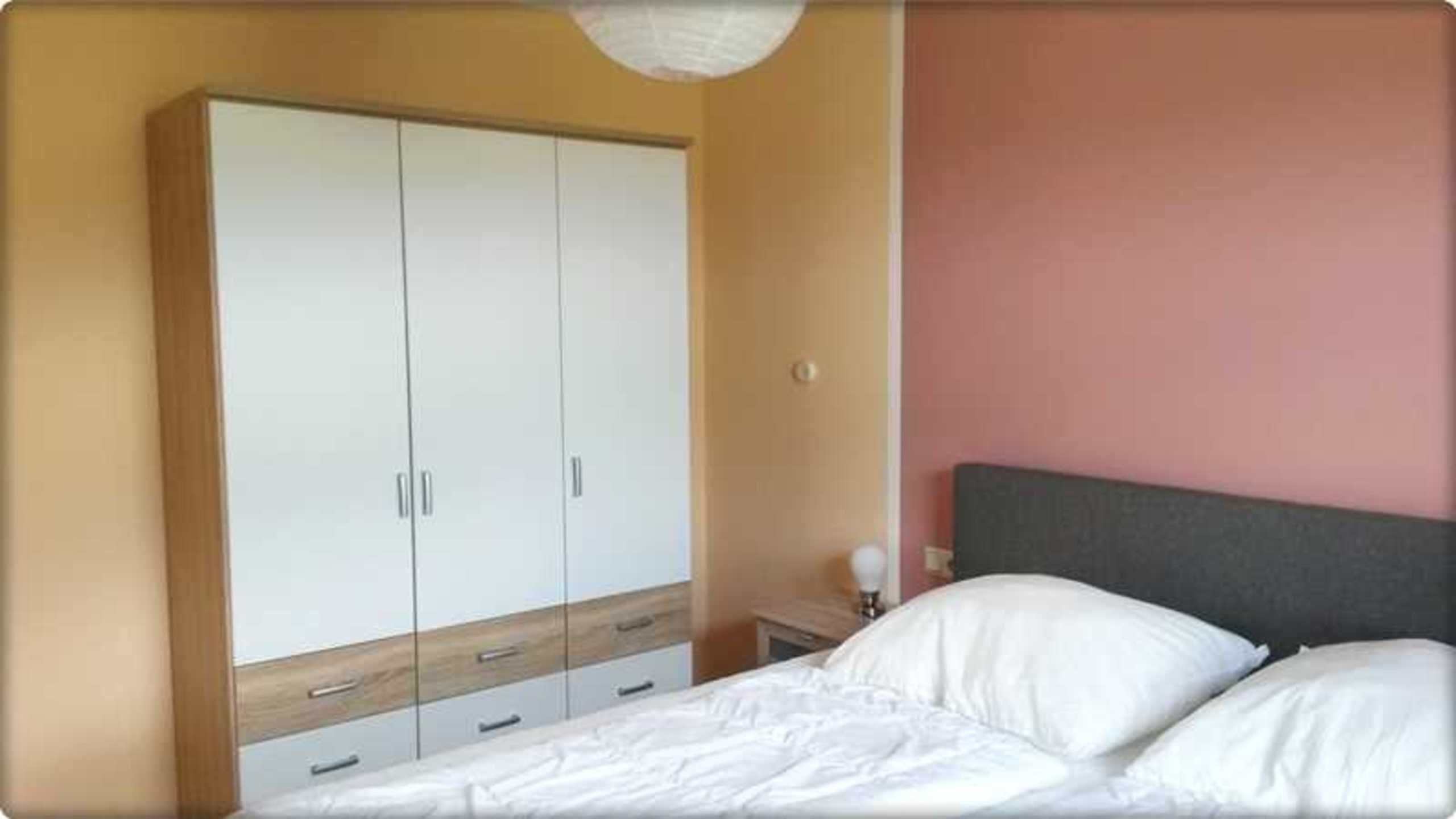 Une chambre à coucher avec un lit, une table de chevet et une armoire.