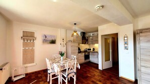 A compact kitchen with modern appliances, a dining area with a patterned tablecloth, and a wooden floor. - MeerZeit, Germany (Prerow)