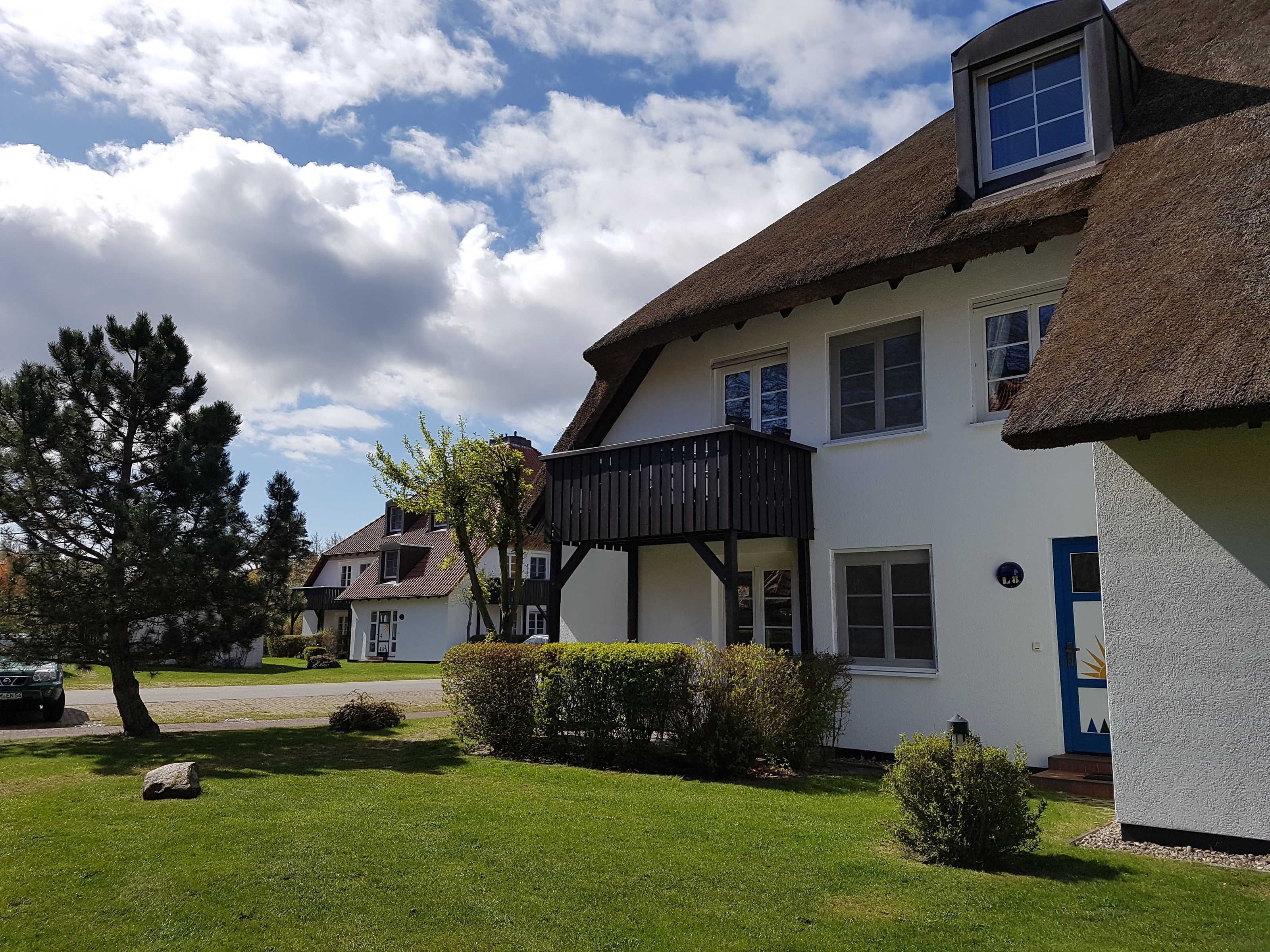 A traditional house with a thatched roof, white walls, and a small balcony.