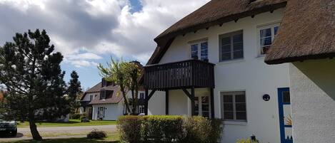 A traditional house with a thatched roof, white walls, and a small balcony.