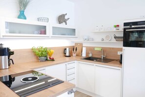 Uma cozinha moderna com armários brancos, fogão preto e bancada de madeira.