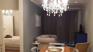 A modern dining area with a wooden table, chairs, and a chandelier. - Dellville Country House (Kareeberg)