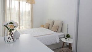 A modern bedroom with a bed, bedside table, and a vase with flowers. - Marina Real I - Denia, Costa Blanca (Denia)