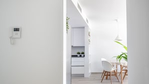 A modern kitchen with white cabinets, a dining area with a table and chairs, and a hanging pendant light. - Marina Real I - Denia, Costa Blanca (Denia)