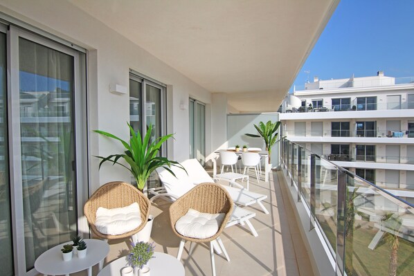 A balcony with wicker chairs, a small table, and potted plants.