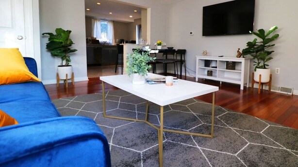 A living room with a blue sofa, a white coffee table, and a grey rug. - BLISSFUL SPACIOUS HOME ⭐ IN HEART OF PRINCETON ⭐ (Princeton)
