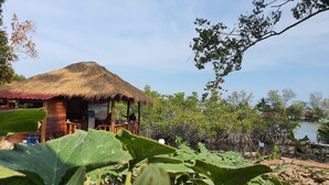 A wooden structure with a thatched roof, surrounded by greenery and a body of water. - 4k Camp Koh Rong (Koh Rong)