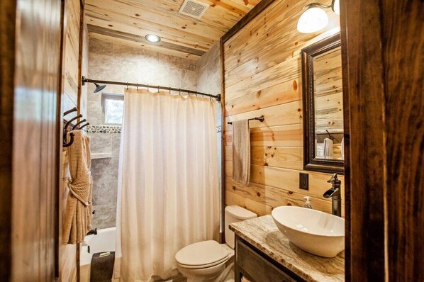 Un baño de madera con inodoro, lavamanos y cortina de ducha.