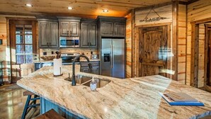 Una cocina con armarios oscuros, electrodomésticos de acero inoxidable y una isla de mármol.