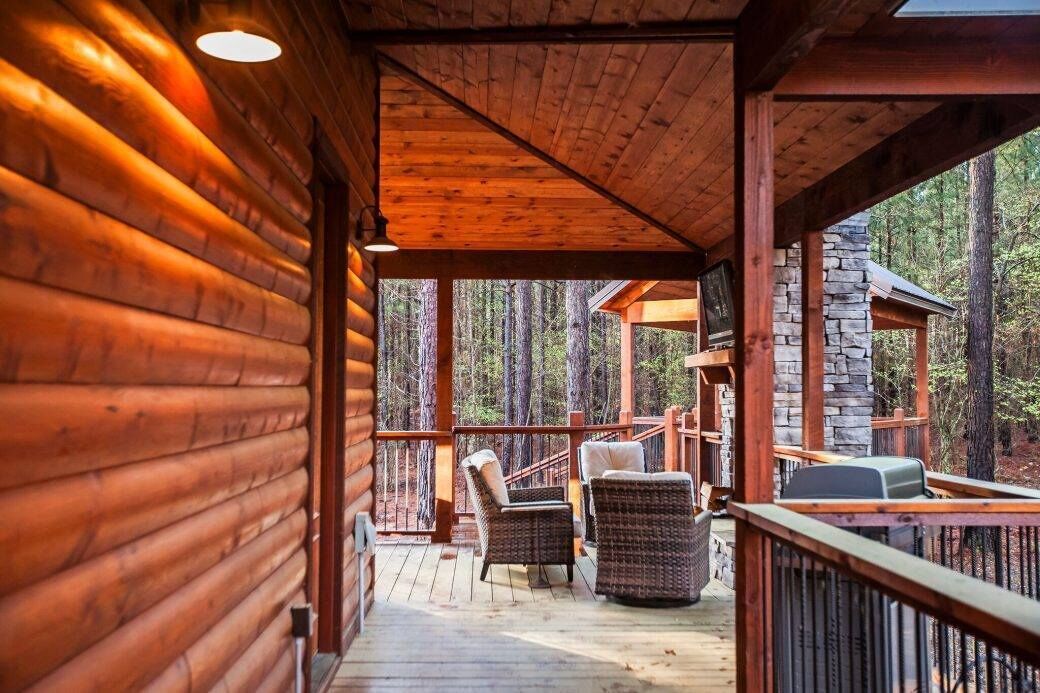 Une cabane en bois dotée d’un porche couvert, de meubles en osier et d’une façade en pierre.