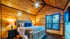 Un dormitorio acogedor con cabaña de madera, una cama, mesitas de noche y una ventana.