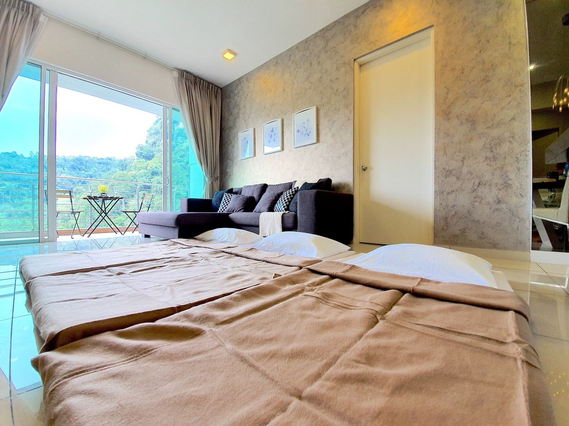 A bedroom with a large bed, a sofa, and a balcony with a table and chairs.