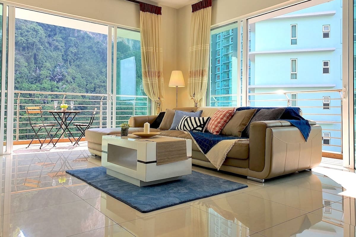A modern living room with a sofa, coffee table, and a balcony with a table and chairs.