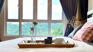 A bed with a wooden tray holding a vase with a flower, two glasses, and a cup. - The Haven Residences by BeeStay at Tambun (Ipoh)