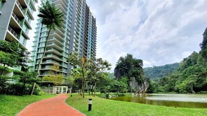 A pathway leading to a high-rise building with a river and forested hills in the background. - The Haven Residences by BeeStay at Tambun (Ipoh)