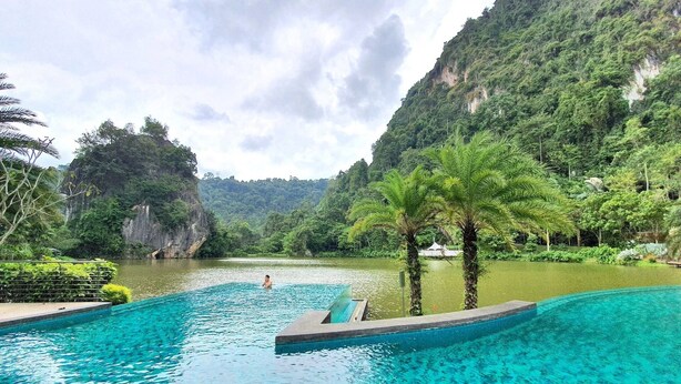 A swimming pool with clear blue water, surrounded by lush greenery and a mountainous backdrop. - The Haven Residences by BeeStay at Tambun (Ipoh)