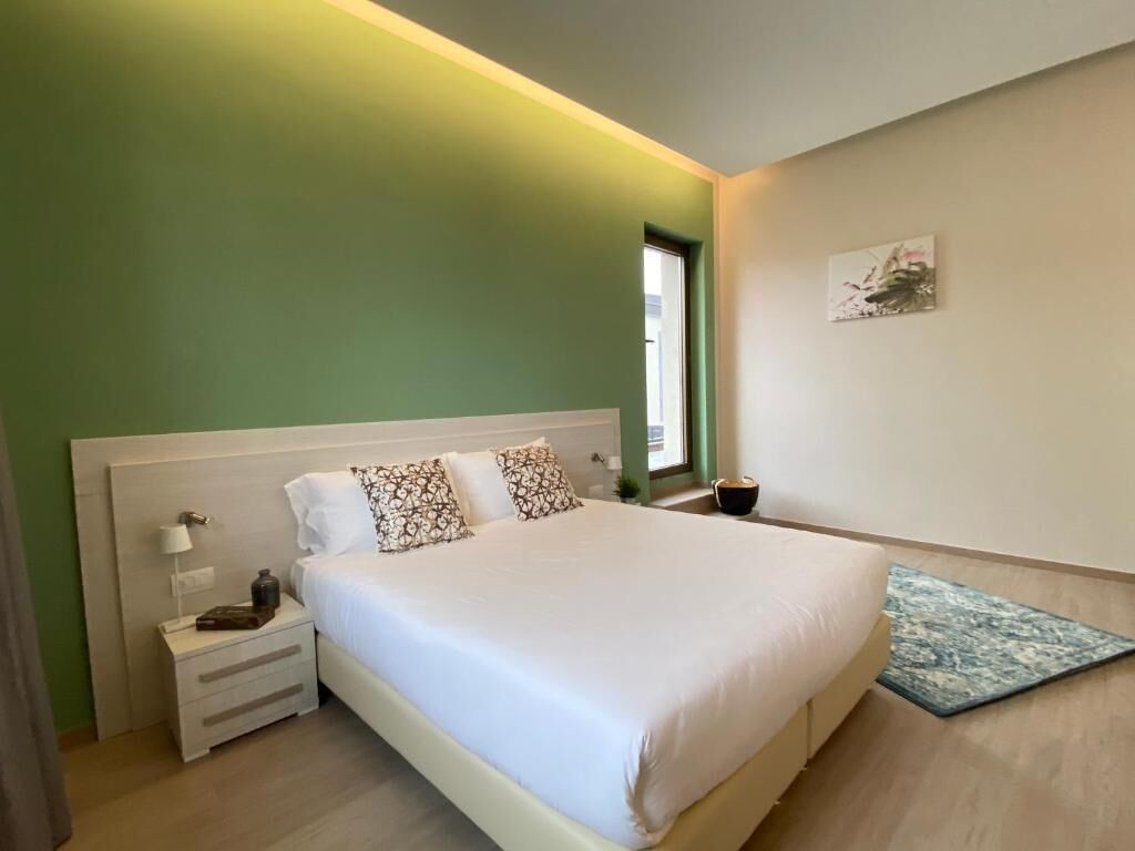 Un dormitorio con una cama grande, una mesita de noche, una lámpara y un cuadro en la pared.
