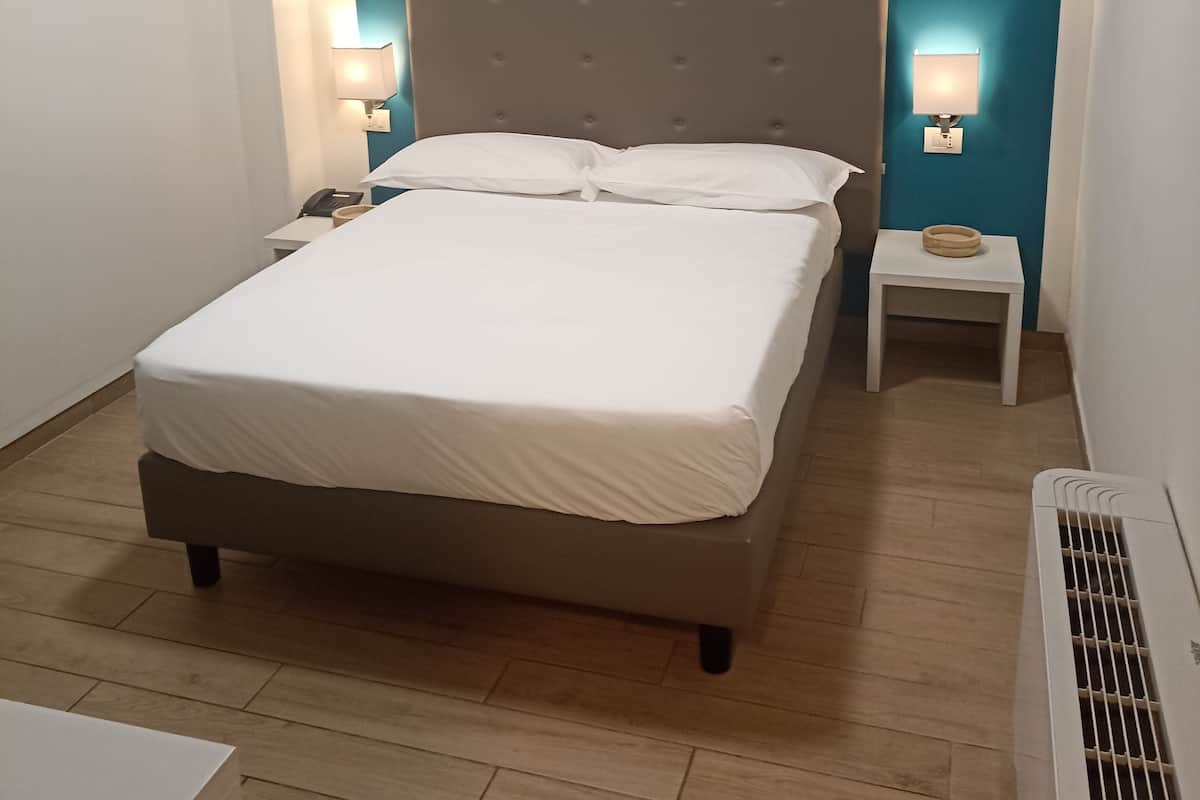 Ein Schlafzimmer mit einem Bett, zwei Nachttischen, einer Heizung und einer Wandleuchte.