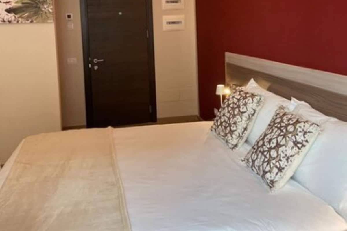 Ein Hotelzimmer mit einem Bett, einer Tür und einer an der Wand befestigten Lampe.
