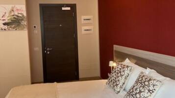 Une chambre d’hôtel avec un lit, une porte et une lampe fixée au mur.
