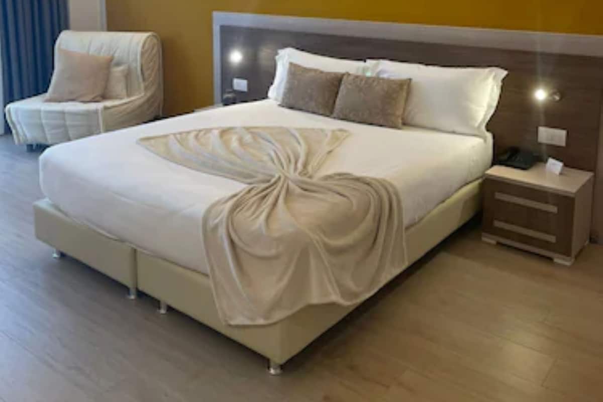 Ein modernes Hotelzimmer mit einem großen Bett, einem Nachttisch, einem Sessel und einer Wand mit einer besonderen Beleuchtung.
