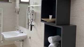 Ein modernes Badezimmer mit Waschbecken, Handtuchhaltern und einem Spiegel.