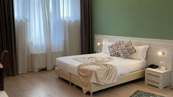 Un dormitorio ordenado con cama, mesitas de noche, escritorio y una alfombra estampada.