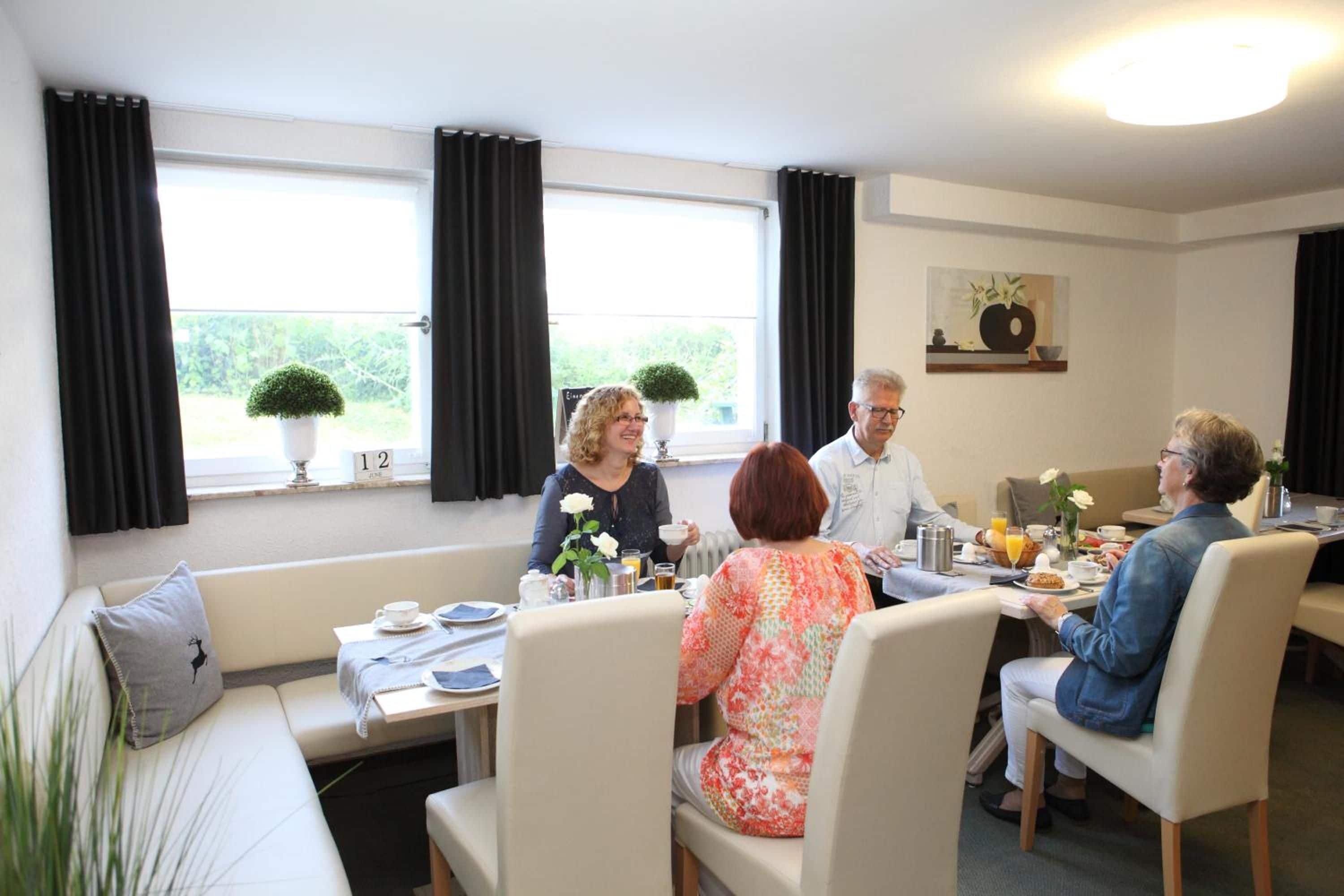 Un coin repas avec une table dressée pour quatre personnes, un canapé et une fenêtre avec des rideaux.