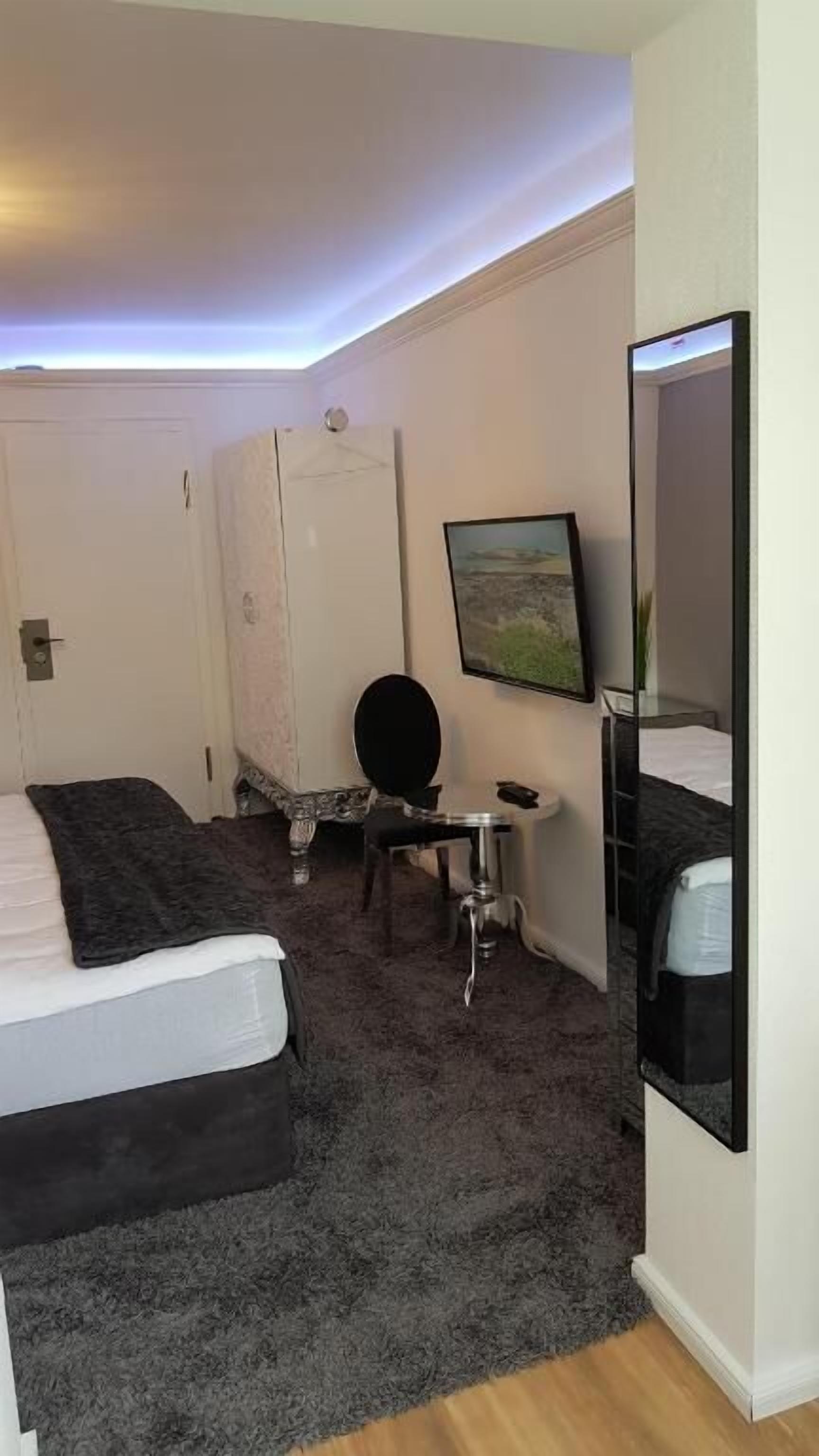 Ein Hotelzimmer mit zwei Betten, einem Schreibtisch, einem Stuhl, einem Spiegel und einem Bild an der Wand.