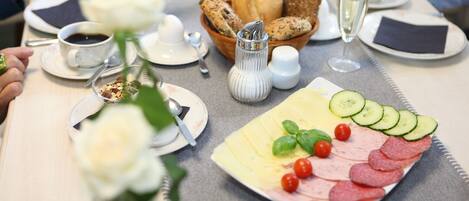 A breakfast setting with a plate of sliced meats, vegetables, and bread.