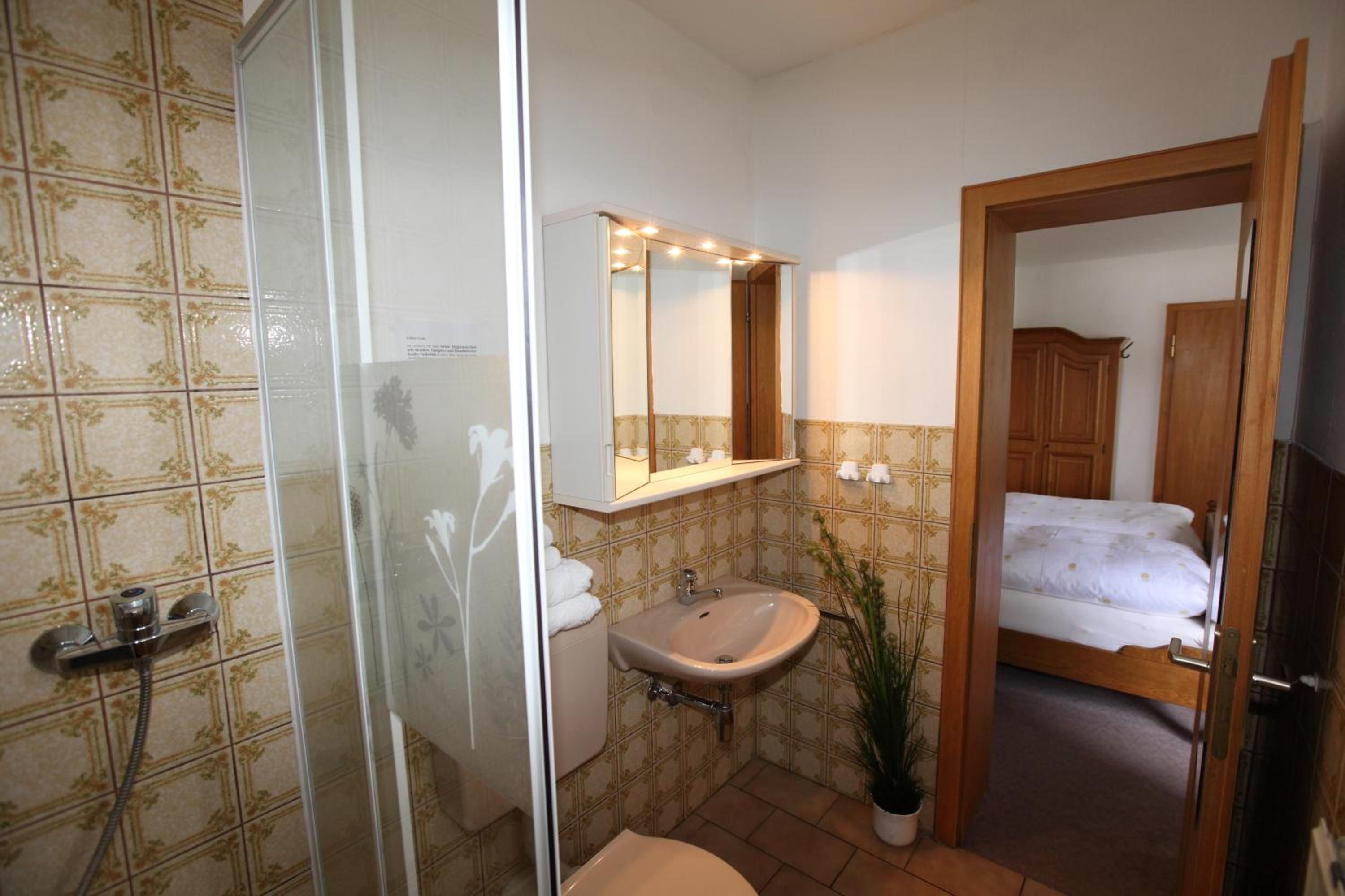 Une salle de bain avec une douche, un lavabo et un miroir au-dessus du lavabo.