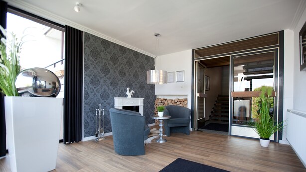 Un salon moderne avec une cheminée, un fauteuil bleu, une table basse blanche et un grand miroir.