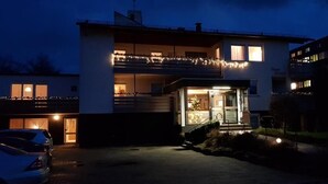 Un bâtiment moderne à deux étages, doté d’un balcon et illuminé de guirlandes lumineuses.