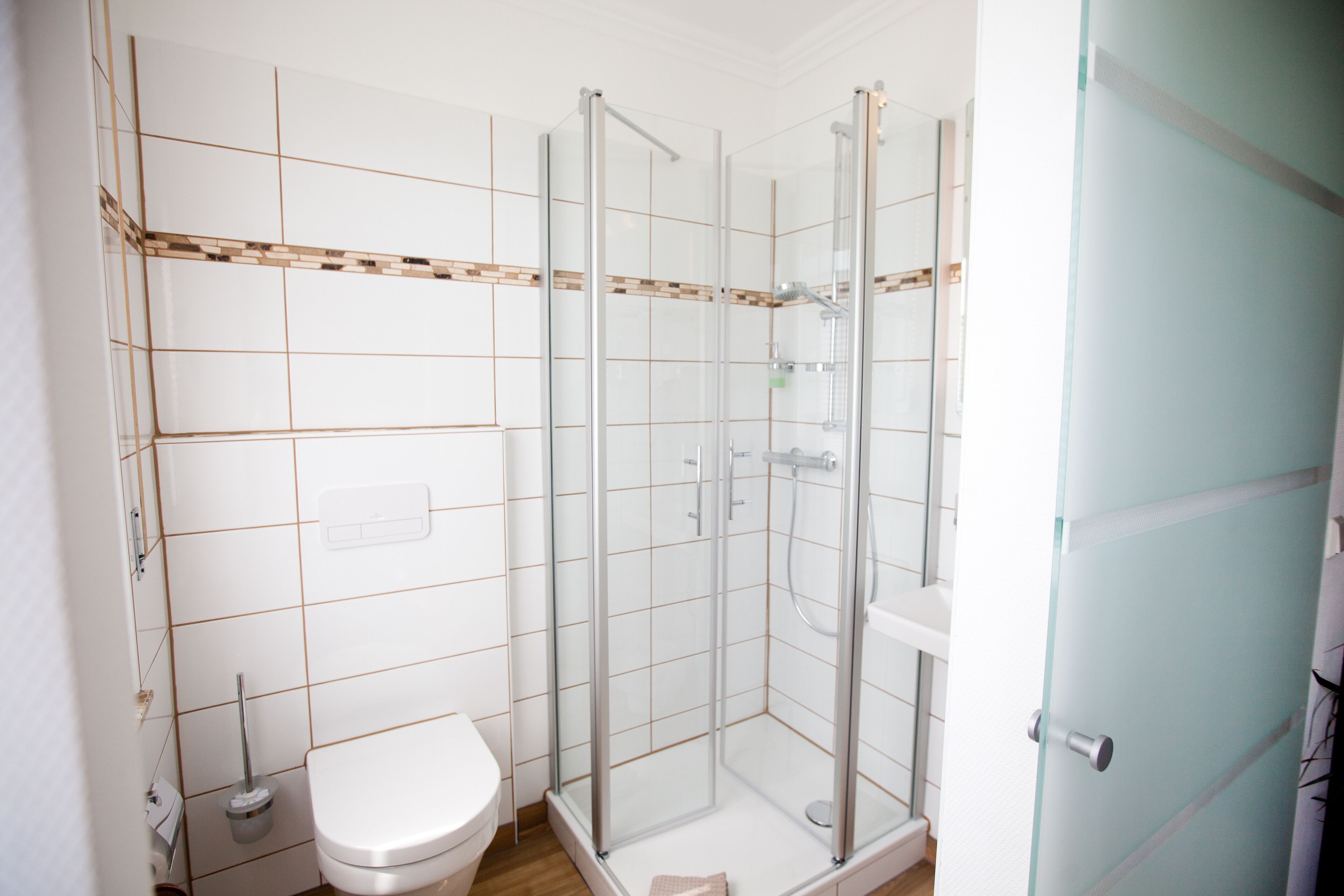 Un baño con ducha de vidrio, inodoro y lavamanos.