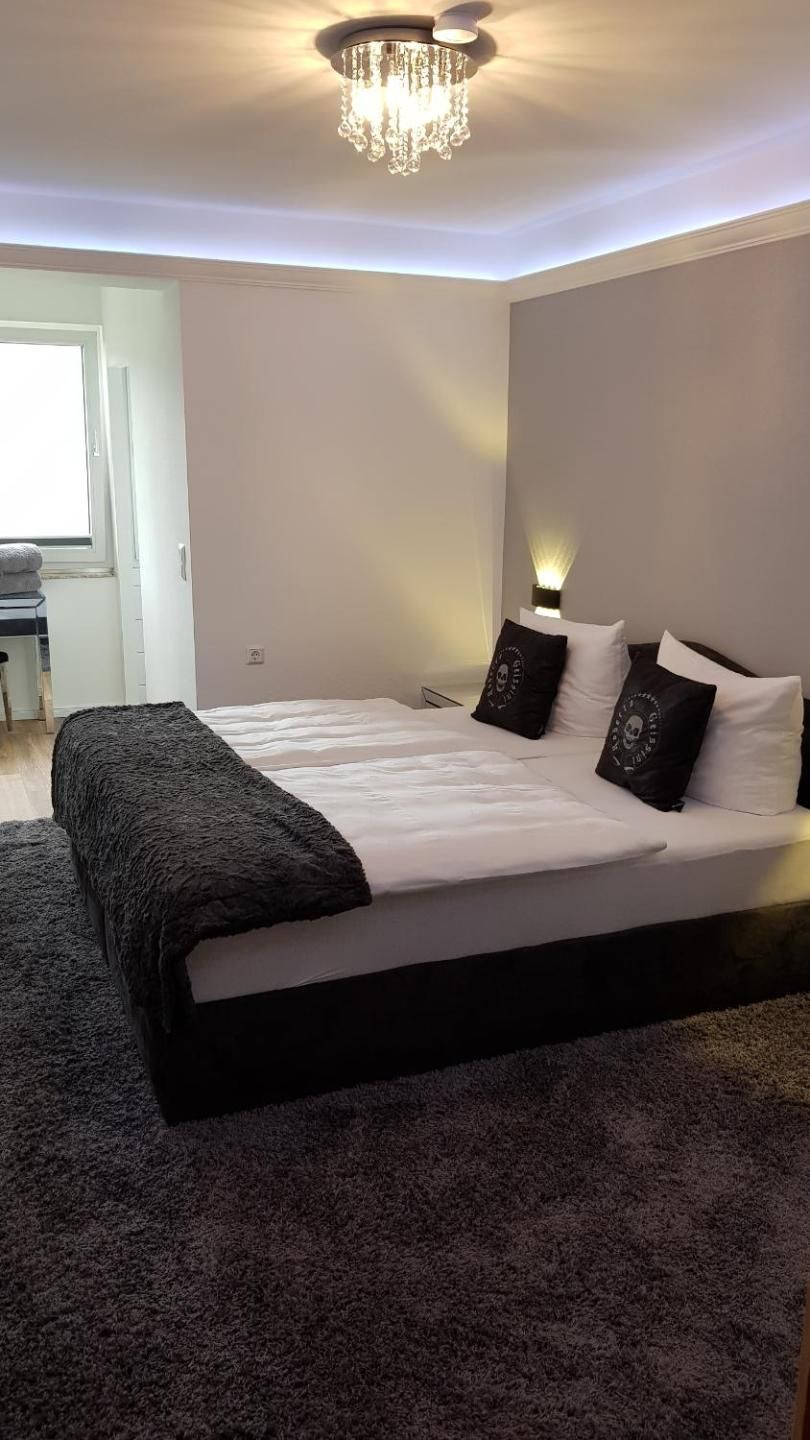 Un dormitorio con una cama grande, dos mesitas de noche, un candelabro y una ventana.
